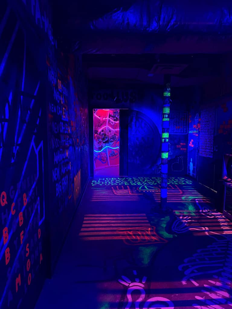 Dark room with black light glowing letters and numbers on the walls and ceilings